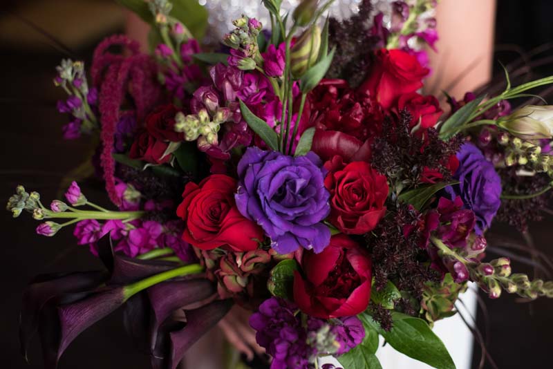 bride holding deep purple and red bridal bouquet