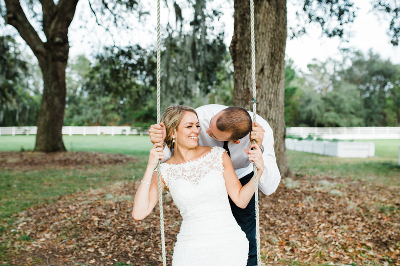 groom pushing bride on tree swing