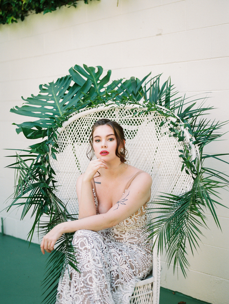 bride sitting on wicker chair with tropical palm leaves