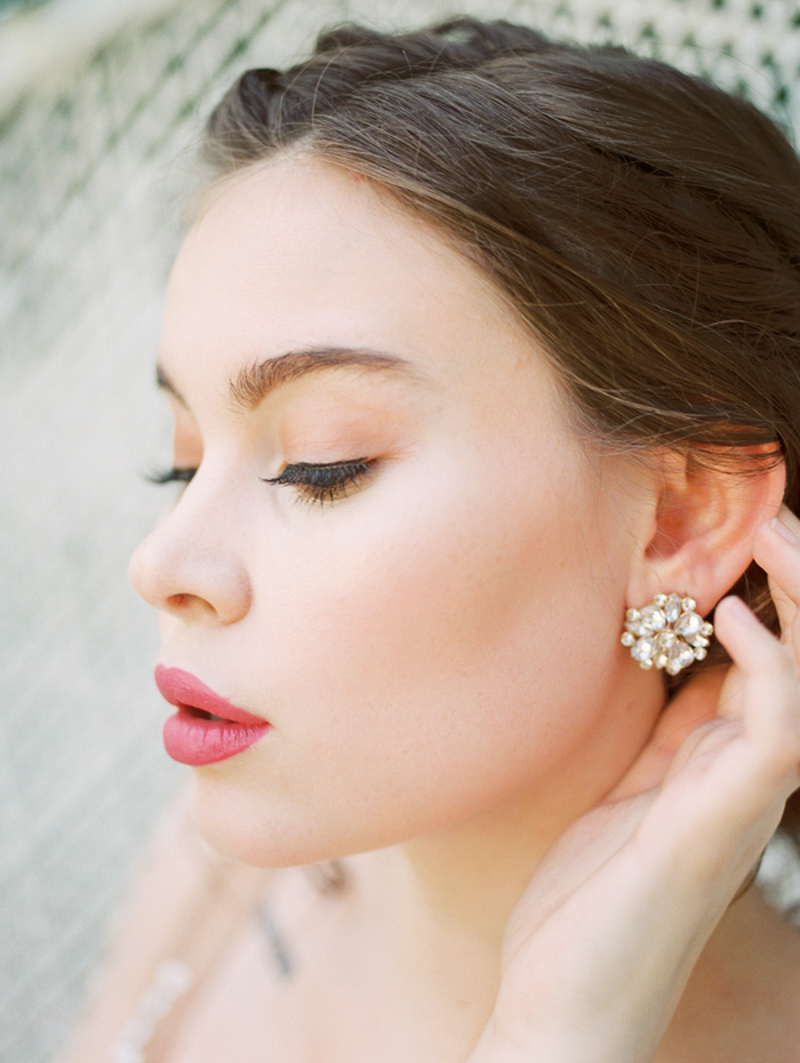 bride holding hair back to show diamond cluster earrings
