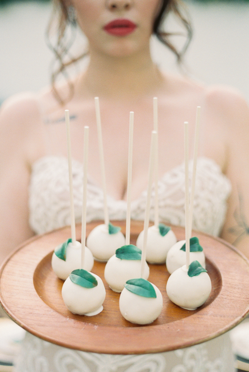 bride holding a plate with white cake balls on them