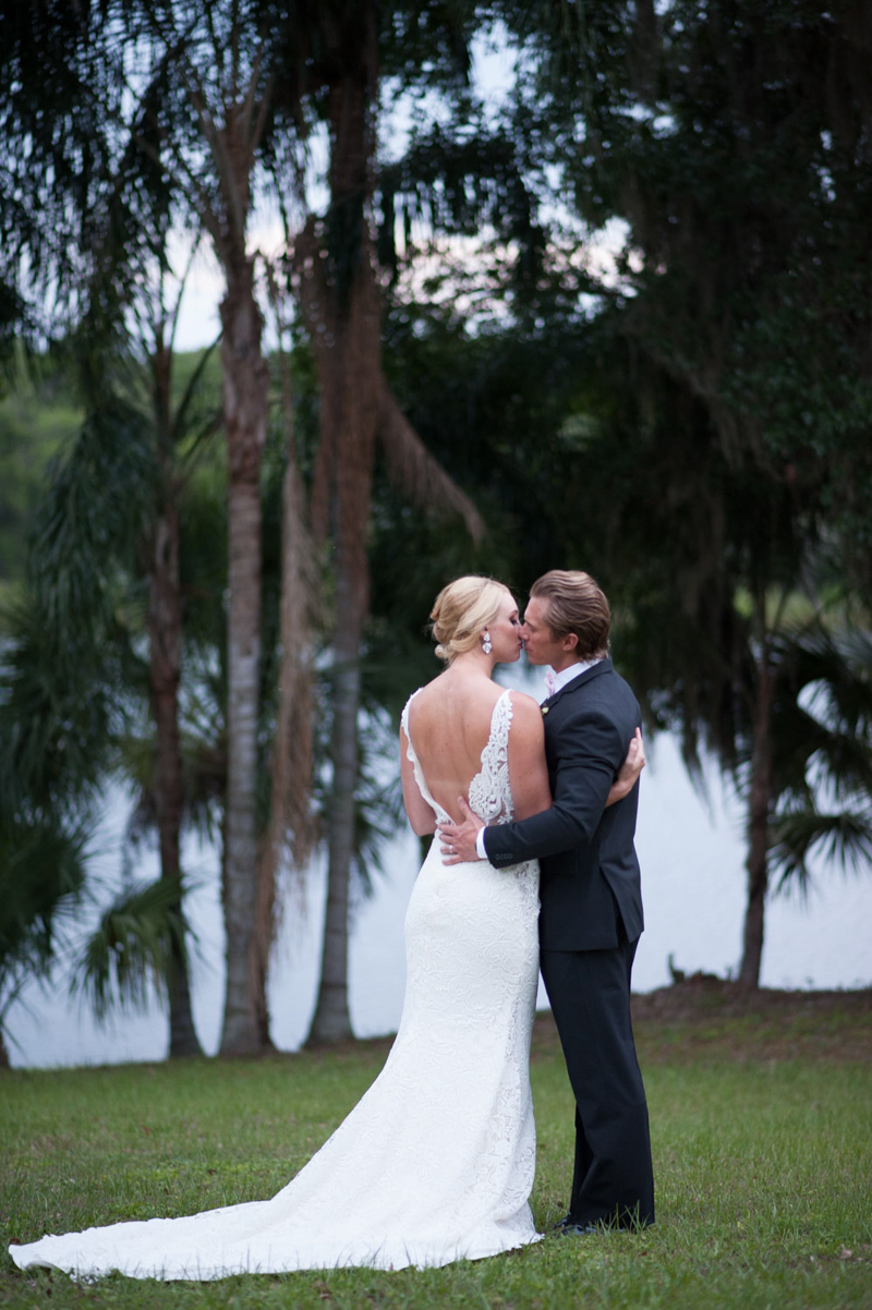 bride and groom kissing next to lake