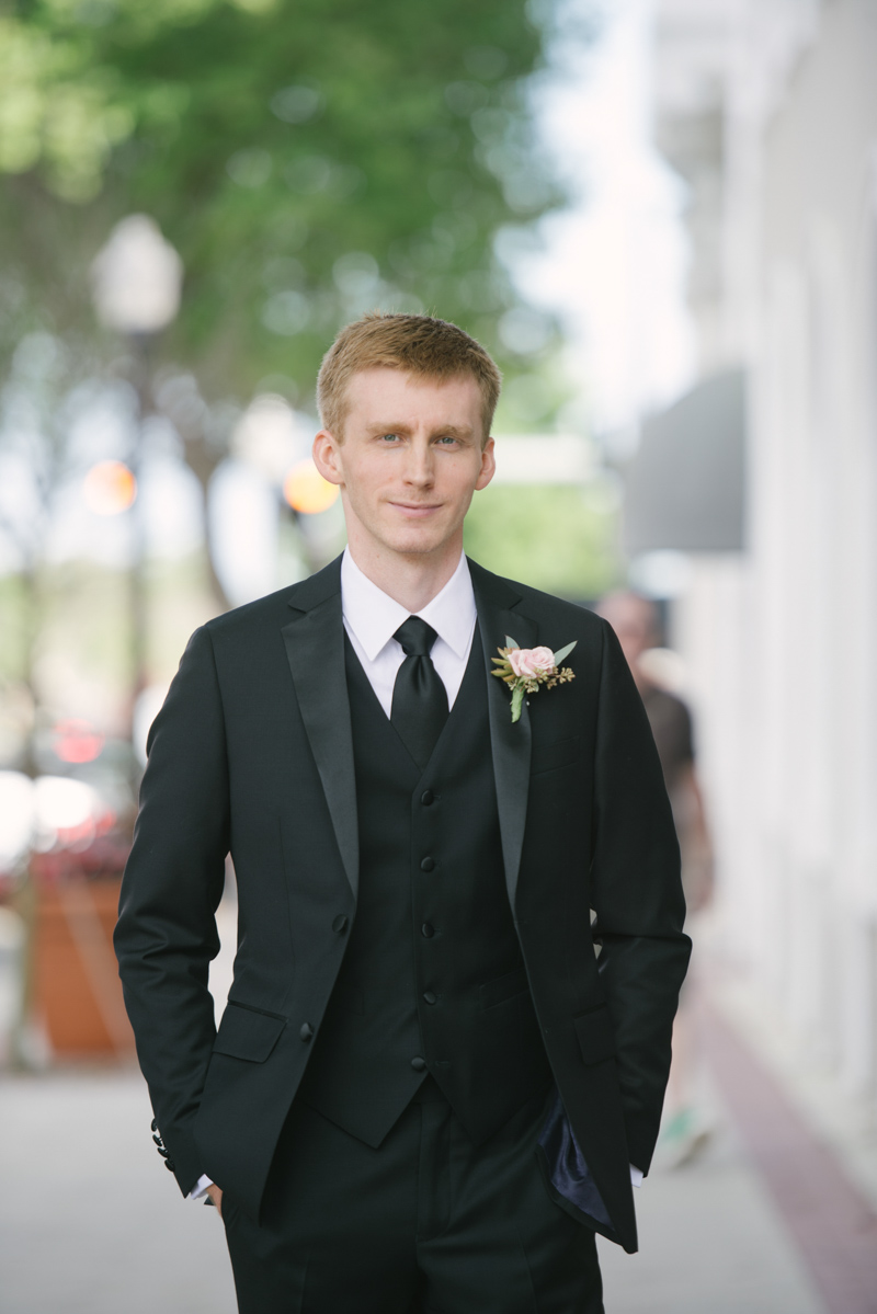 groom in black tax with pink boutonniere