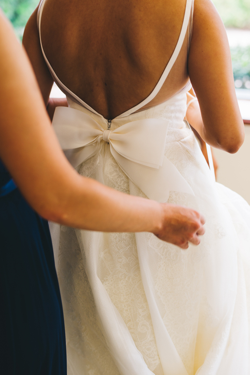 bridesmaid fixing bow on bridal gown