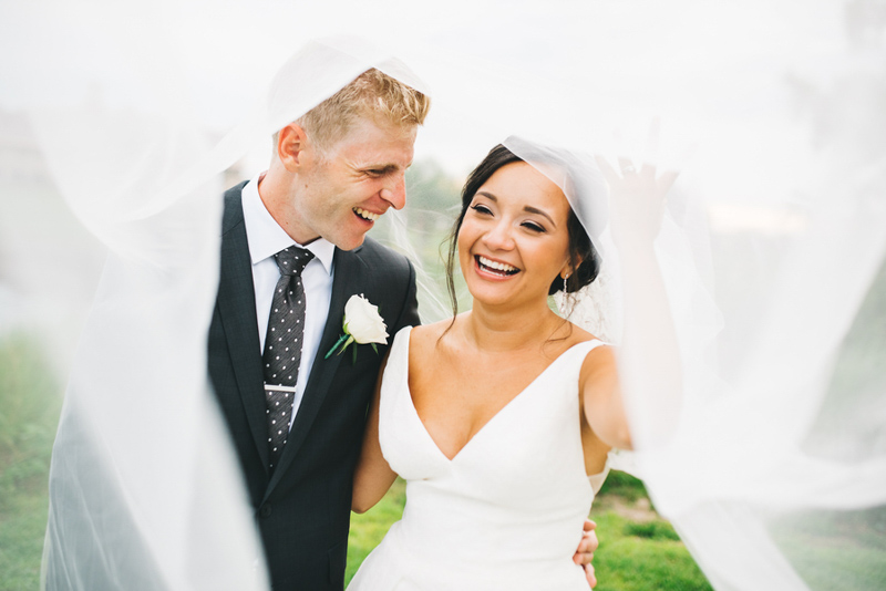 couple laughing under bridal veil