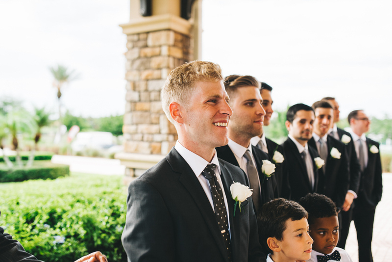 groom smiling at bride walking down aisle