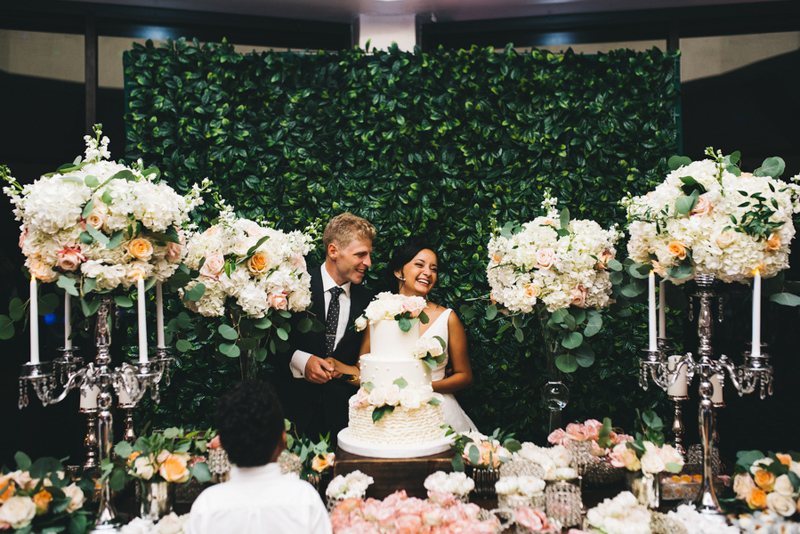bride and groom laughing while cutting wedding cake
