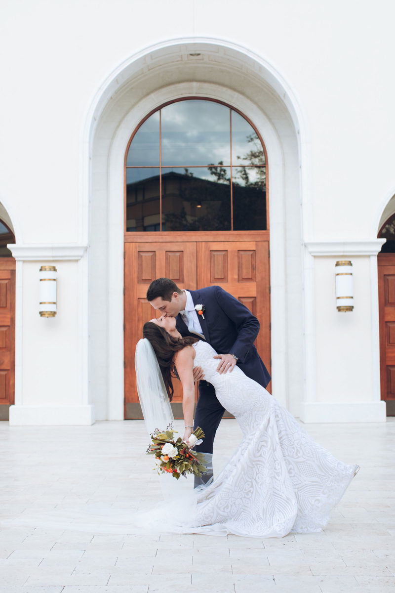 bride and groom kissing in front of St. Margaret Mary's Catholic Church
