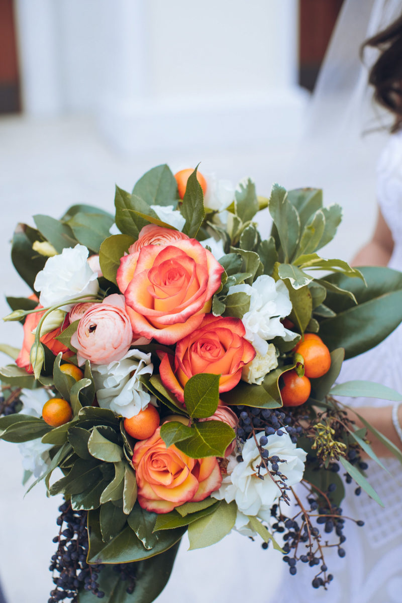 bride holding orange rose bouquet by Weddings by Carly ane's