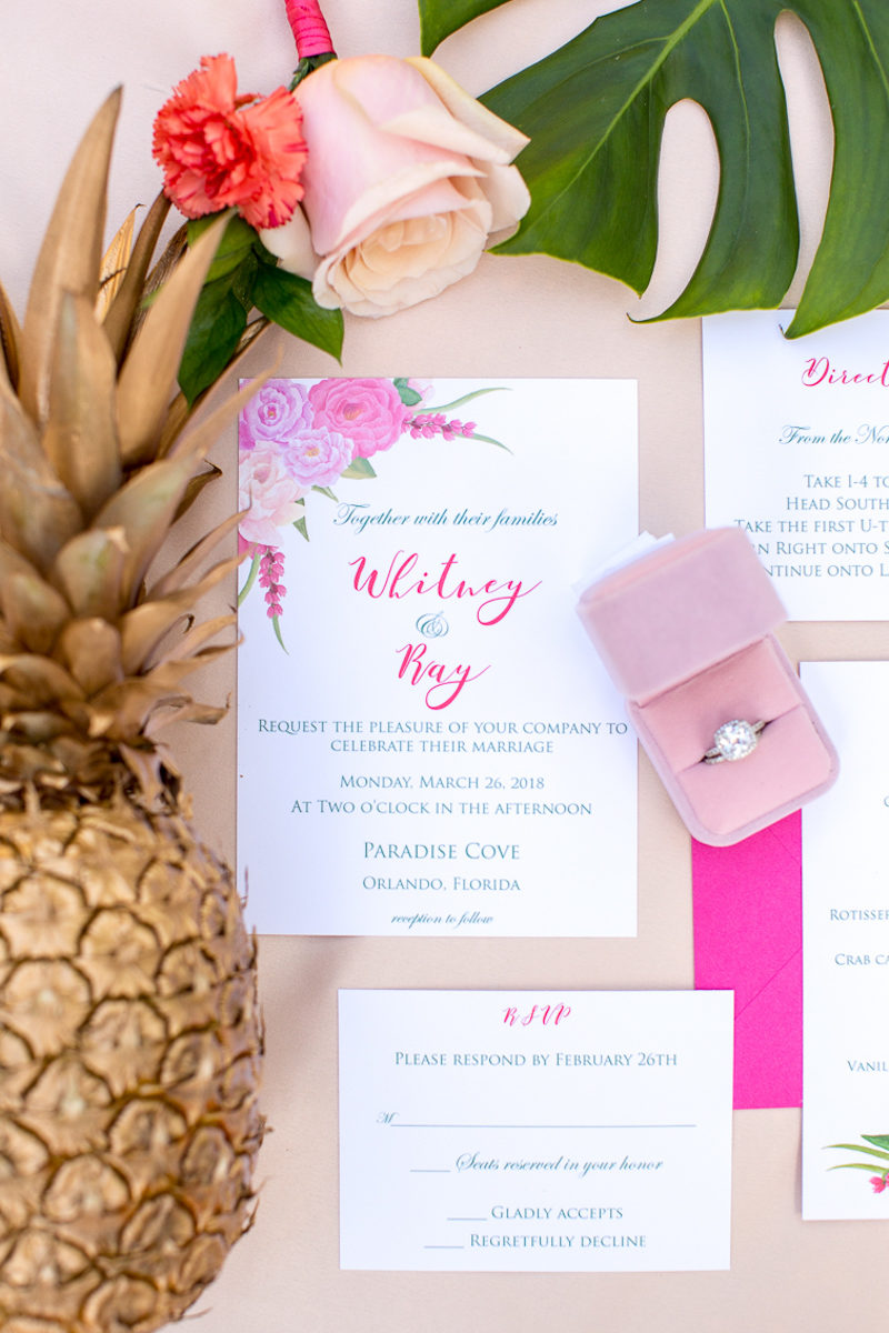pink wedding invitations next to a golden pineapple