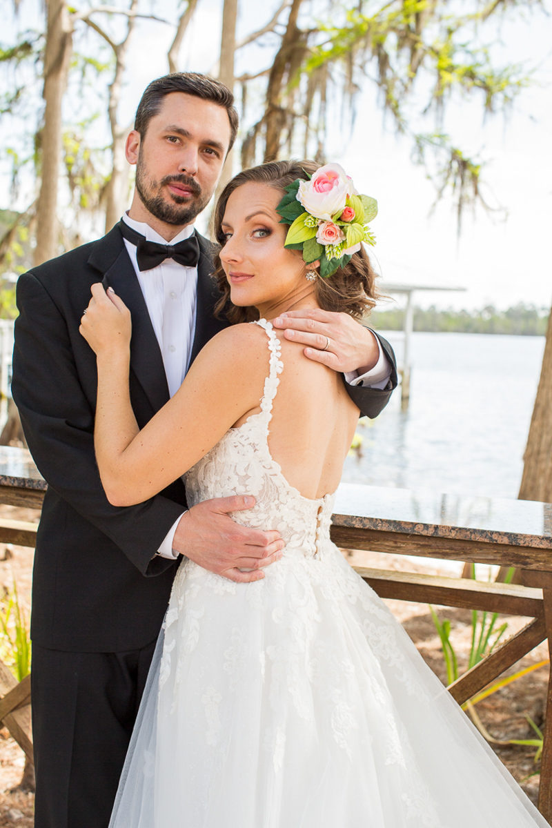 groom in black tux hugging bride with love floral hairpiece