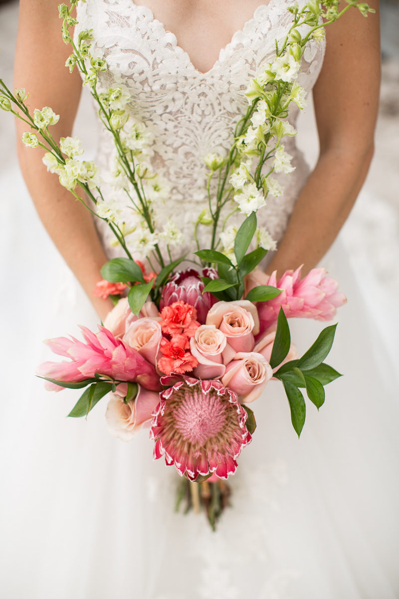 bride holding tropical wedding bouquet with king protea