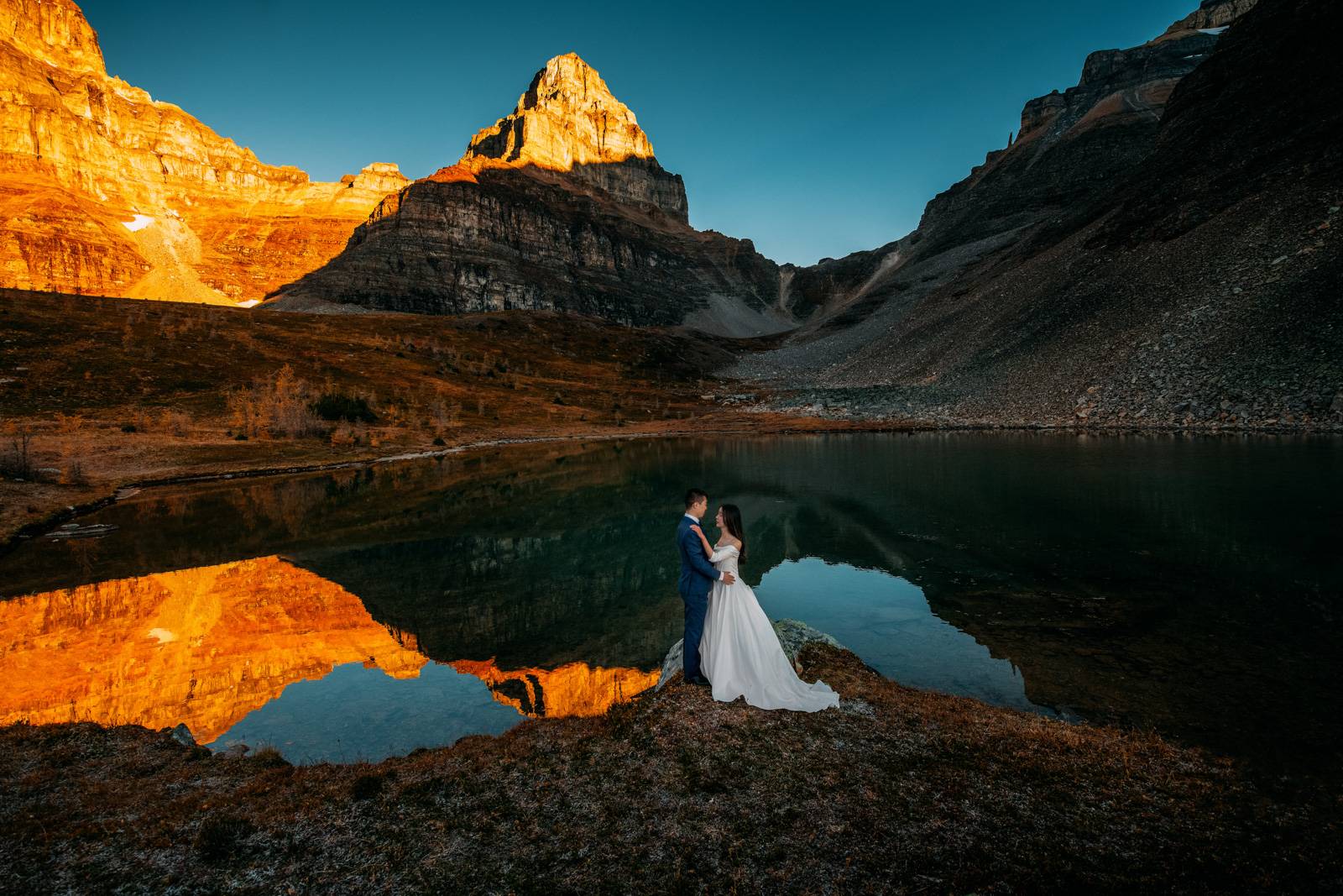 married couple hold each other after sunrise adventure hiking in the mountains