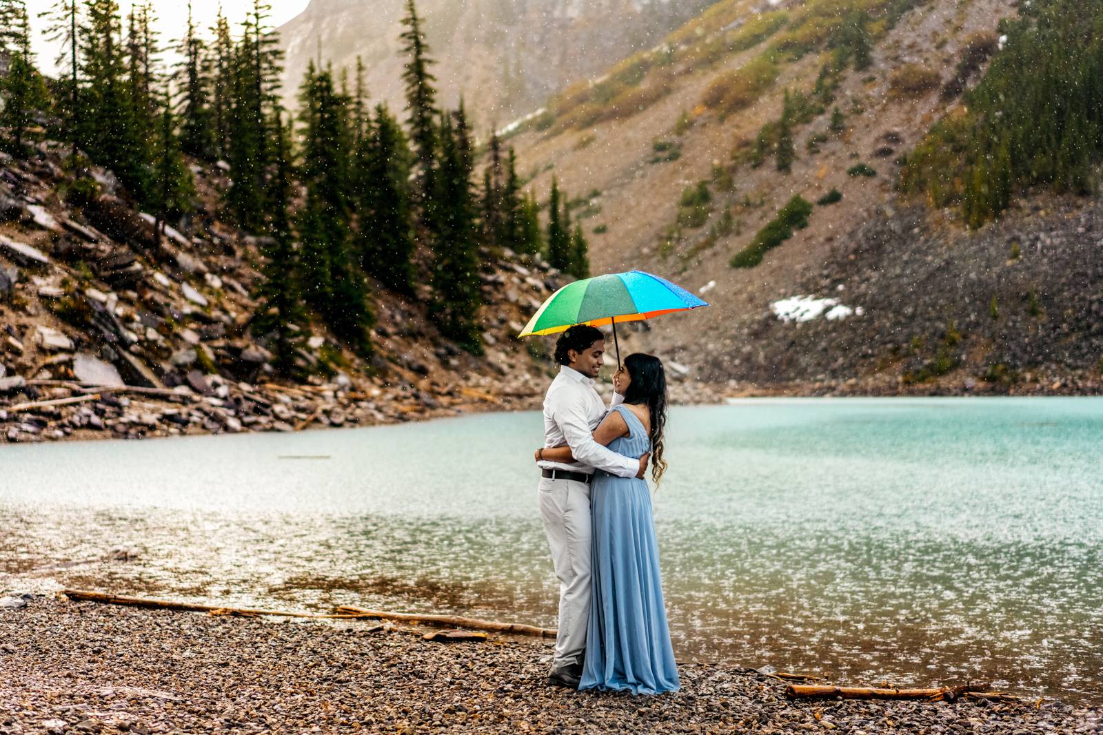 couple holding umbrella in the rain in the mountains