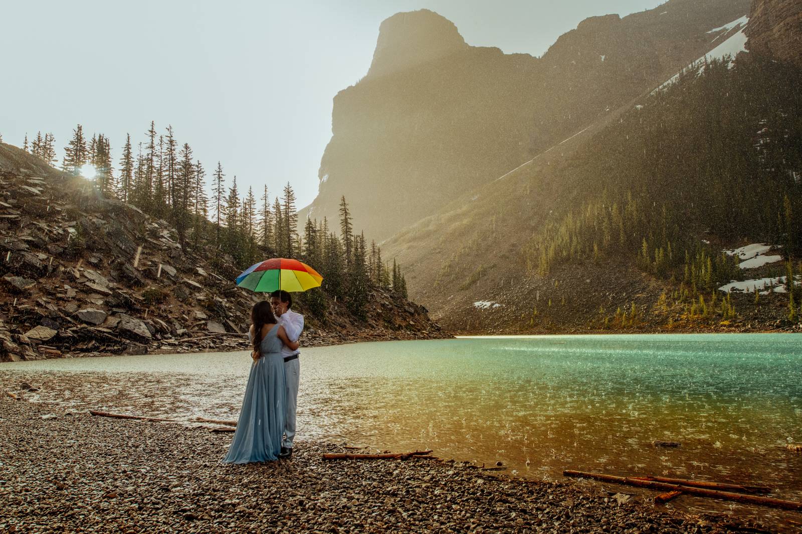 couple holding umbrella in the rain at moraine lake