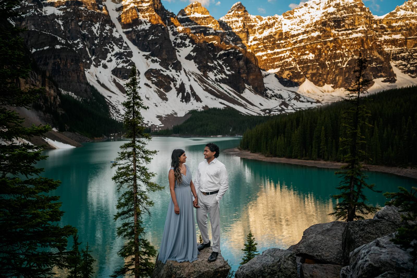 couple holding hands at moraine lake during sunrise