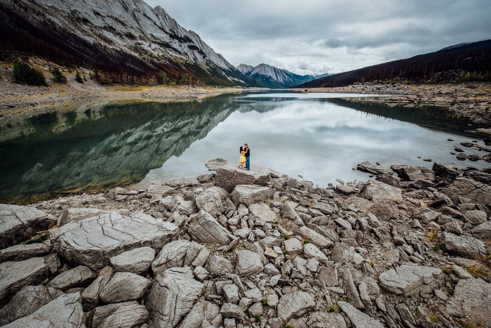Engaged couple enjoying  stunning view of Medicine Lake in Jasper.