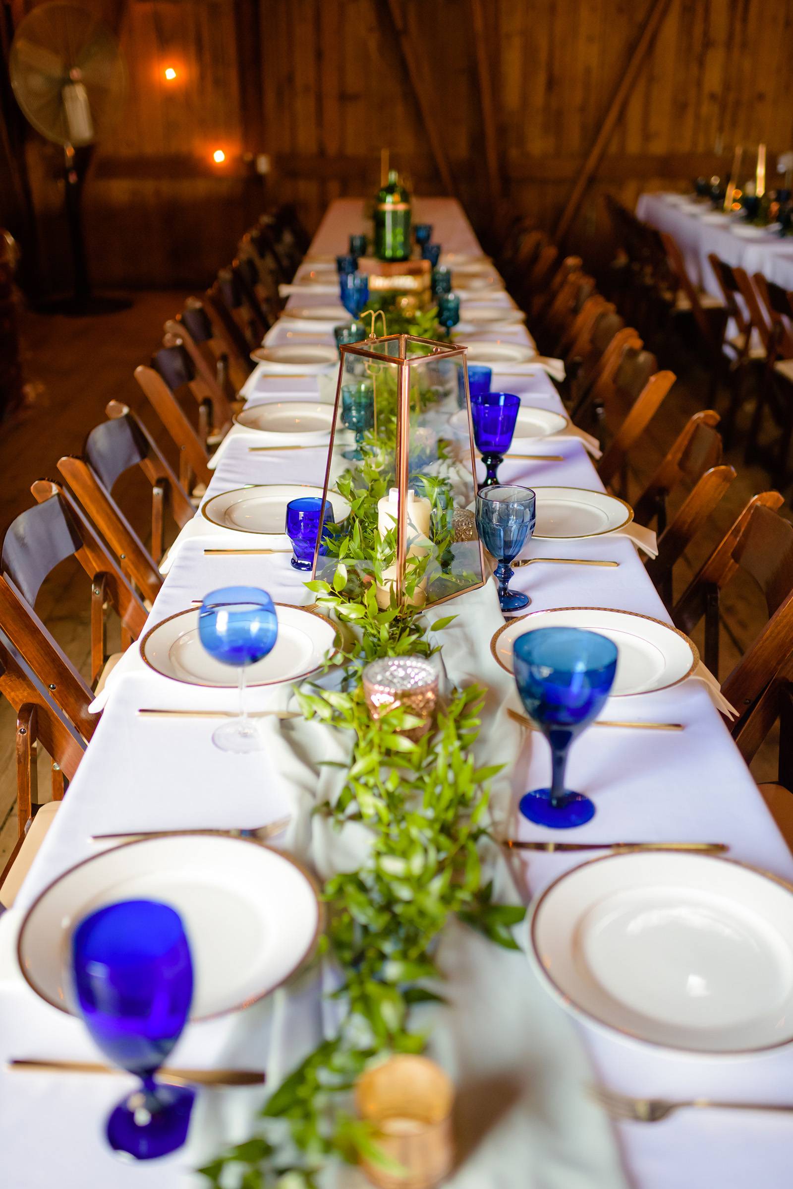 reception table decor, table setting, table settings, blue glassware, greenery, wood chairs