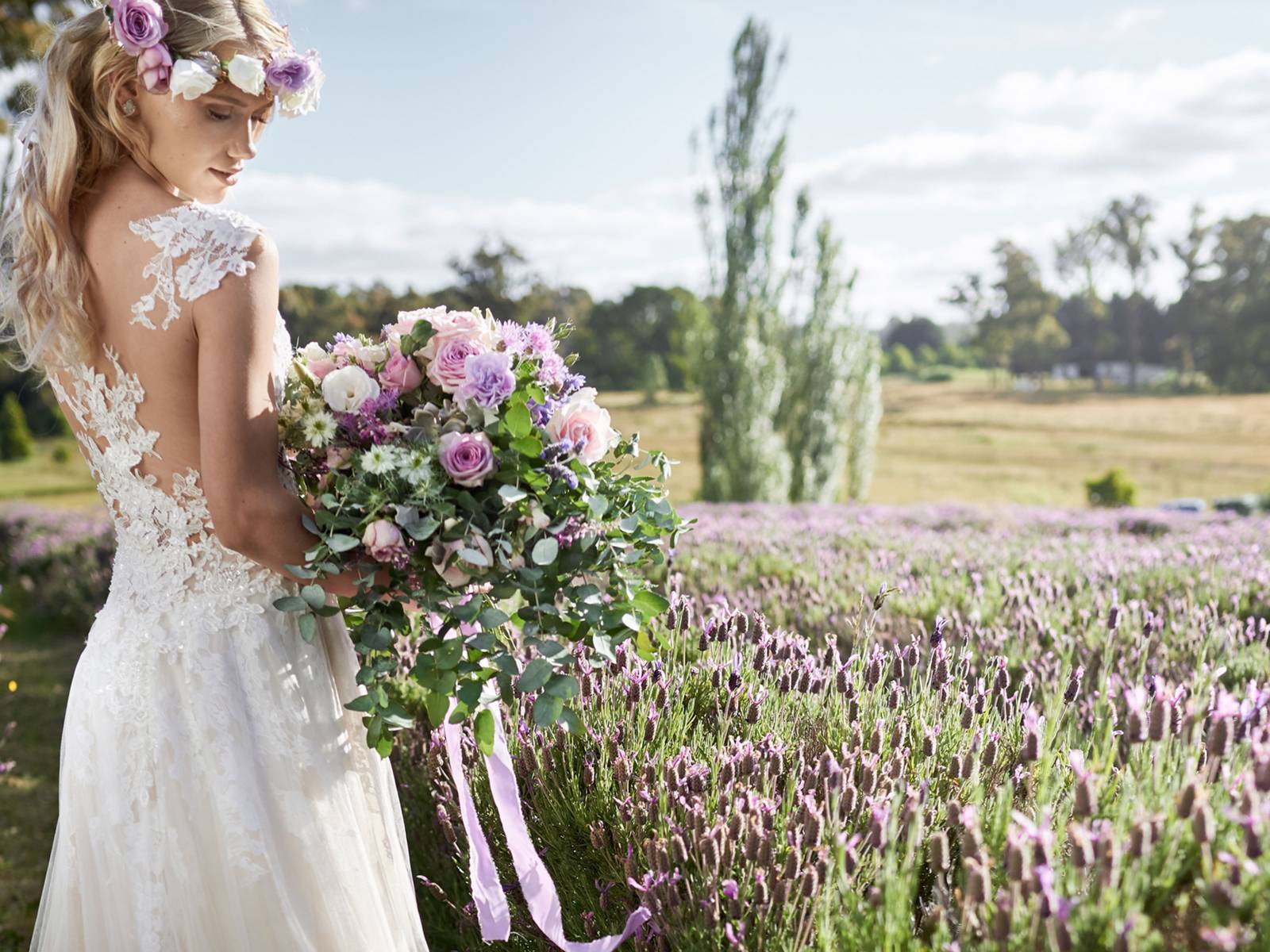 Bride holding large lavender and pink bouquet, standing in a lavender field.