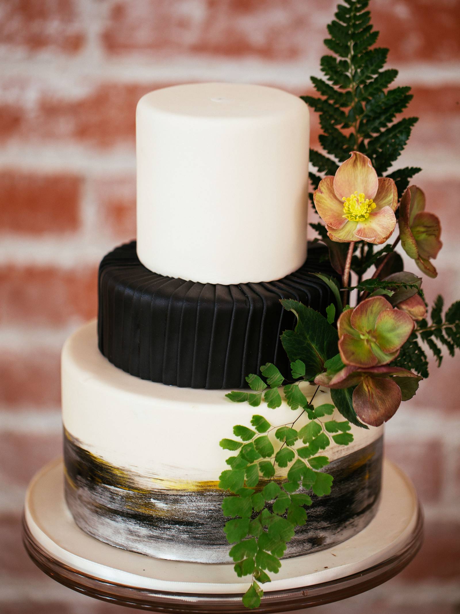 Black and white, three-tiered wedding cake accented with greenery