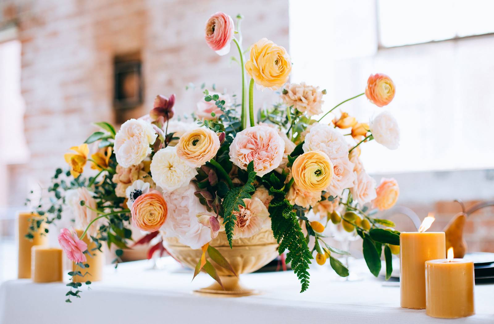 Lush peach, pink, yellow and coral centerpiece of peonies, ranunculus and greenery