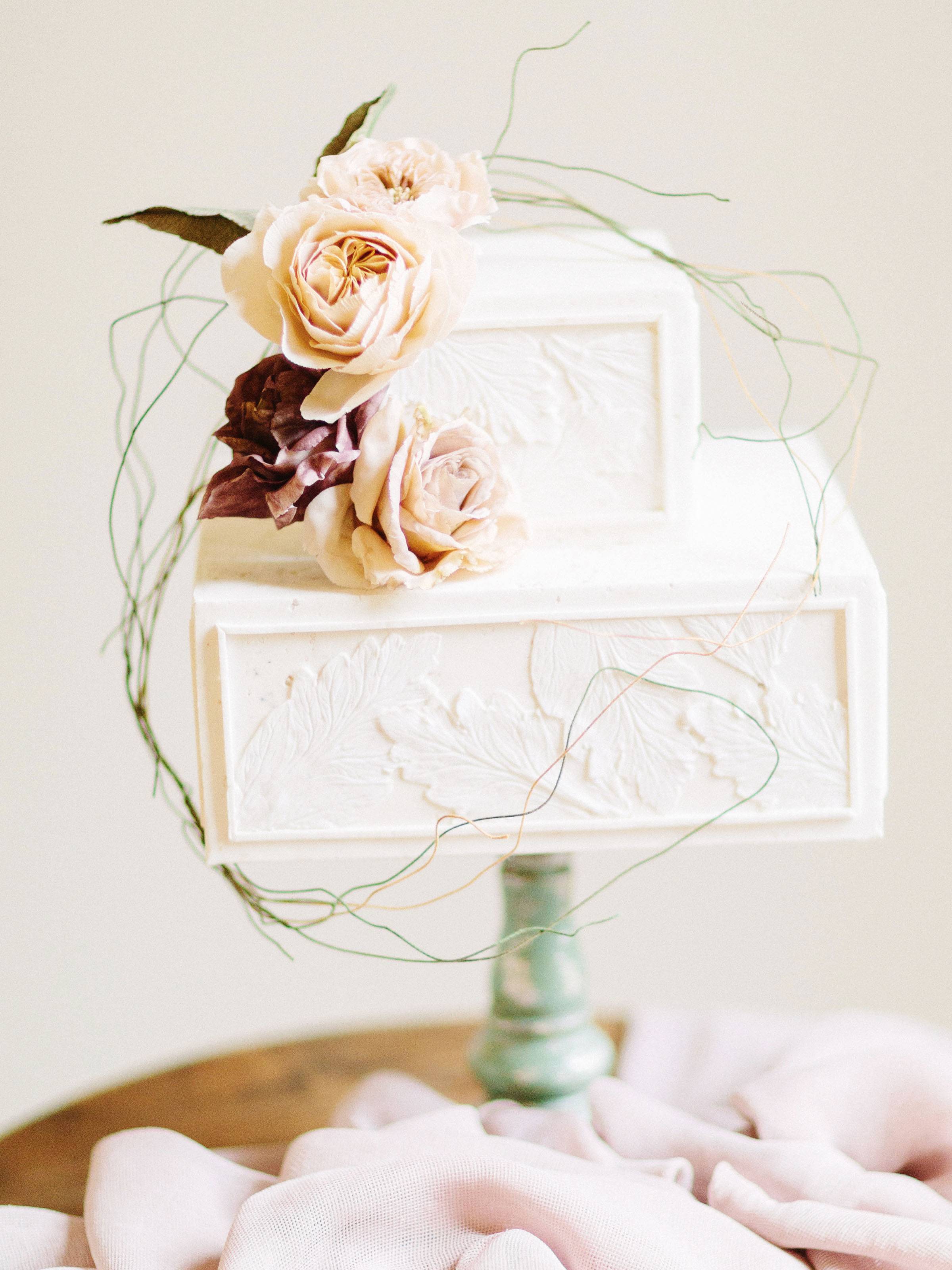 Two-tiered, square, ivory cake with blush flower accents