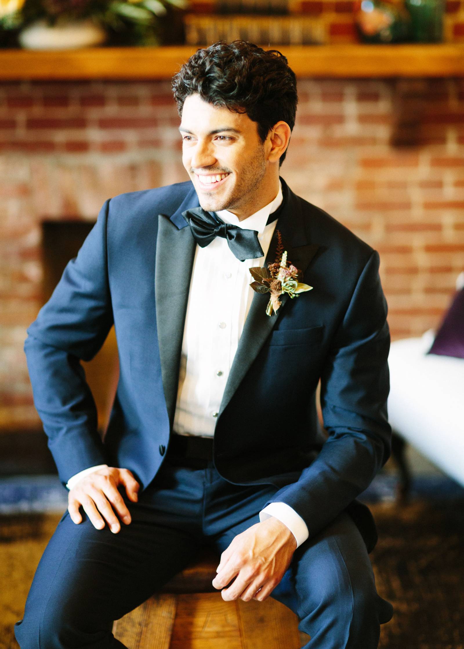 Groom in navy blue tuxedo with black lapels and bow tie