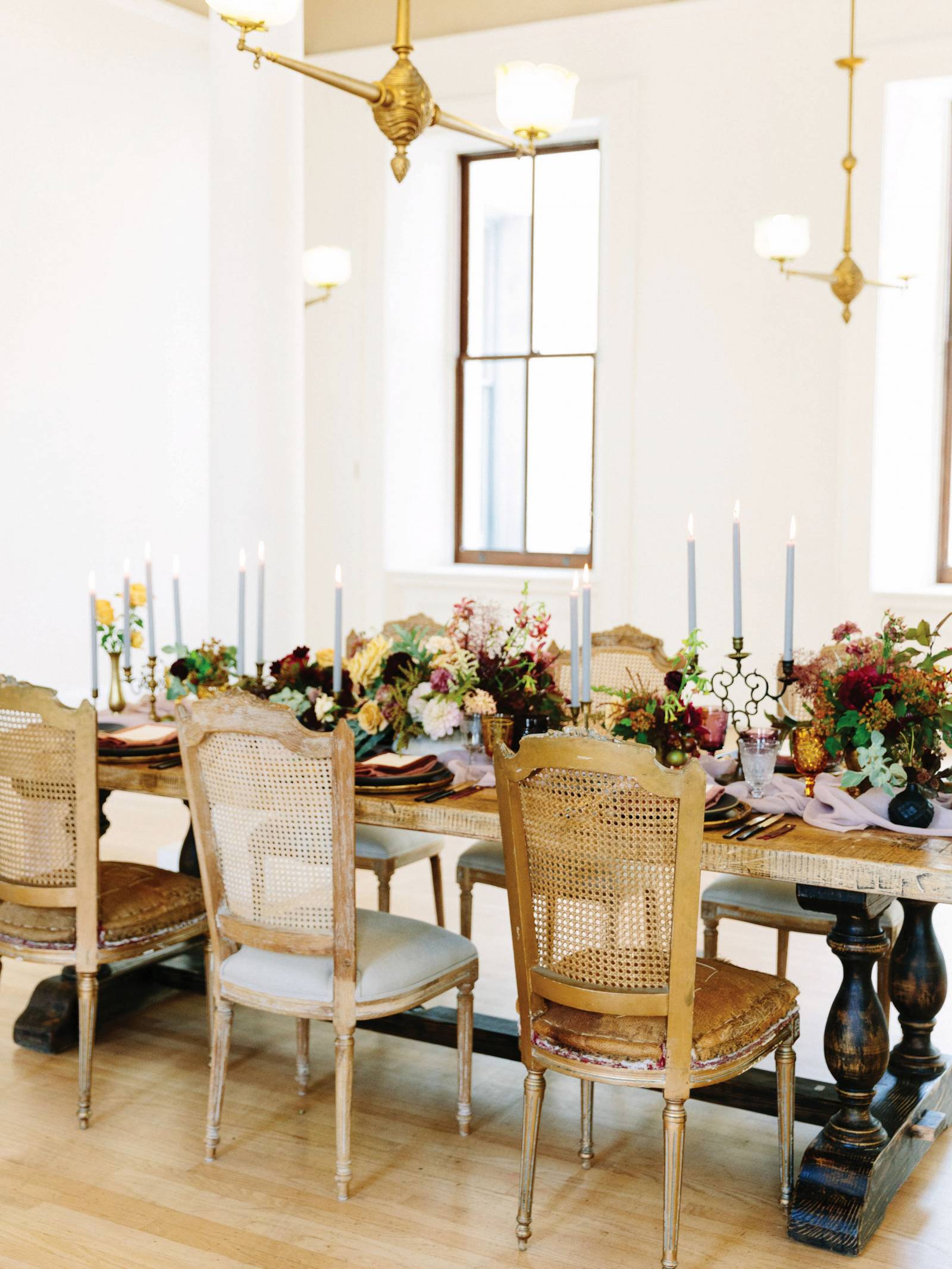 rustic table with fall flowers, black plates and vases, vintage chairs and lavender tapered candles
