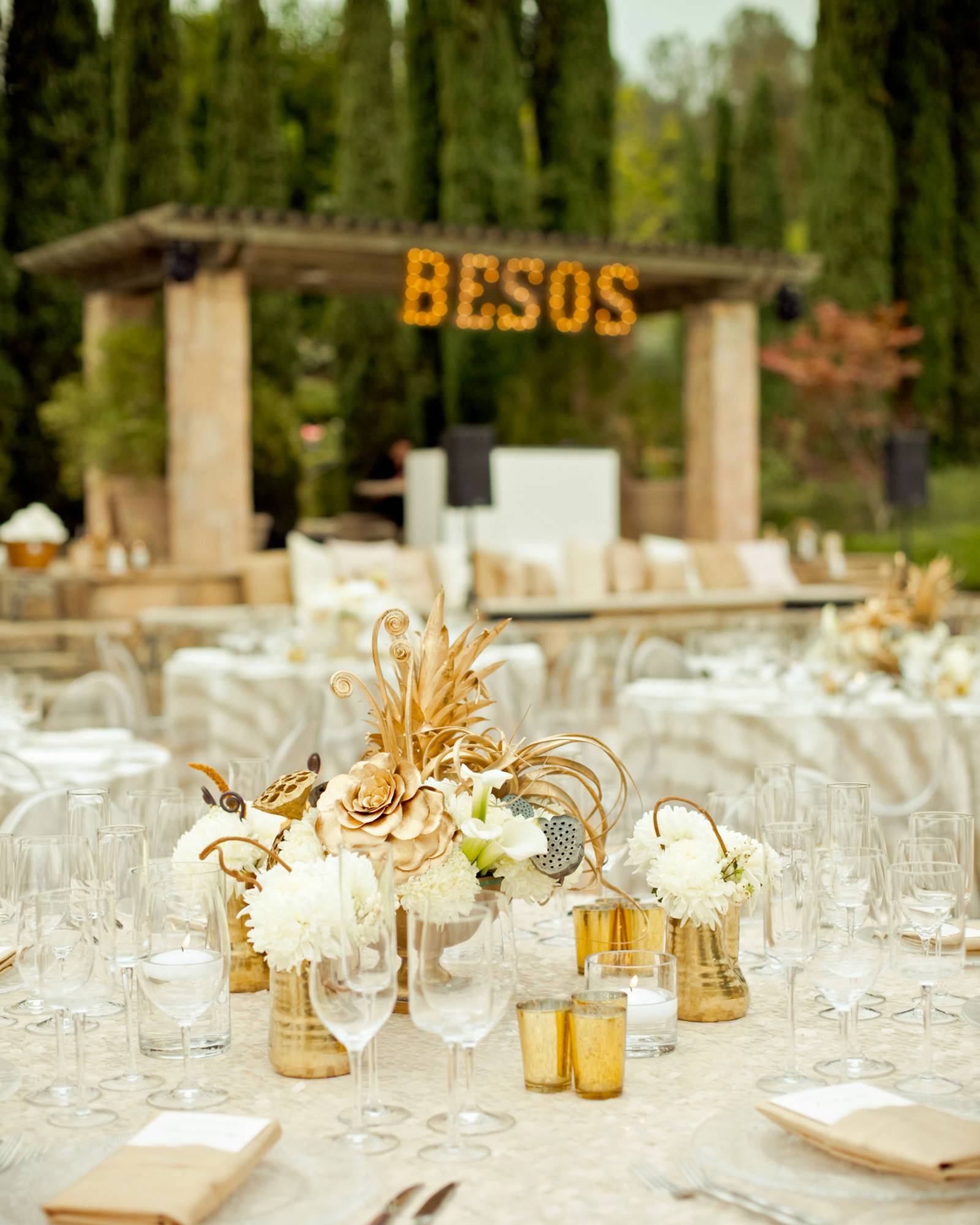 white and gold centerpiece surrounded by gold votives and small vases