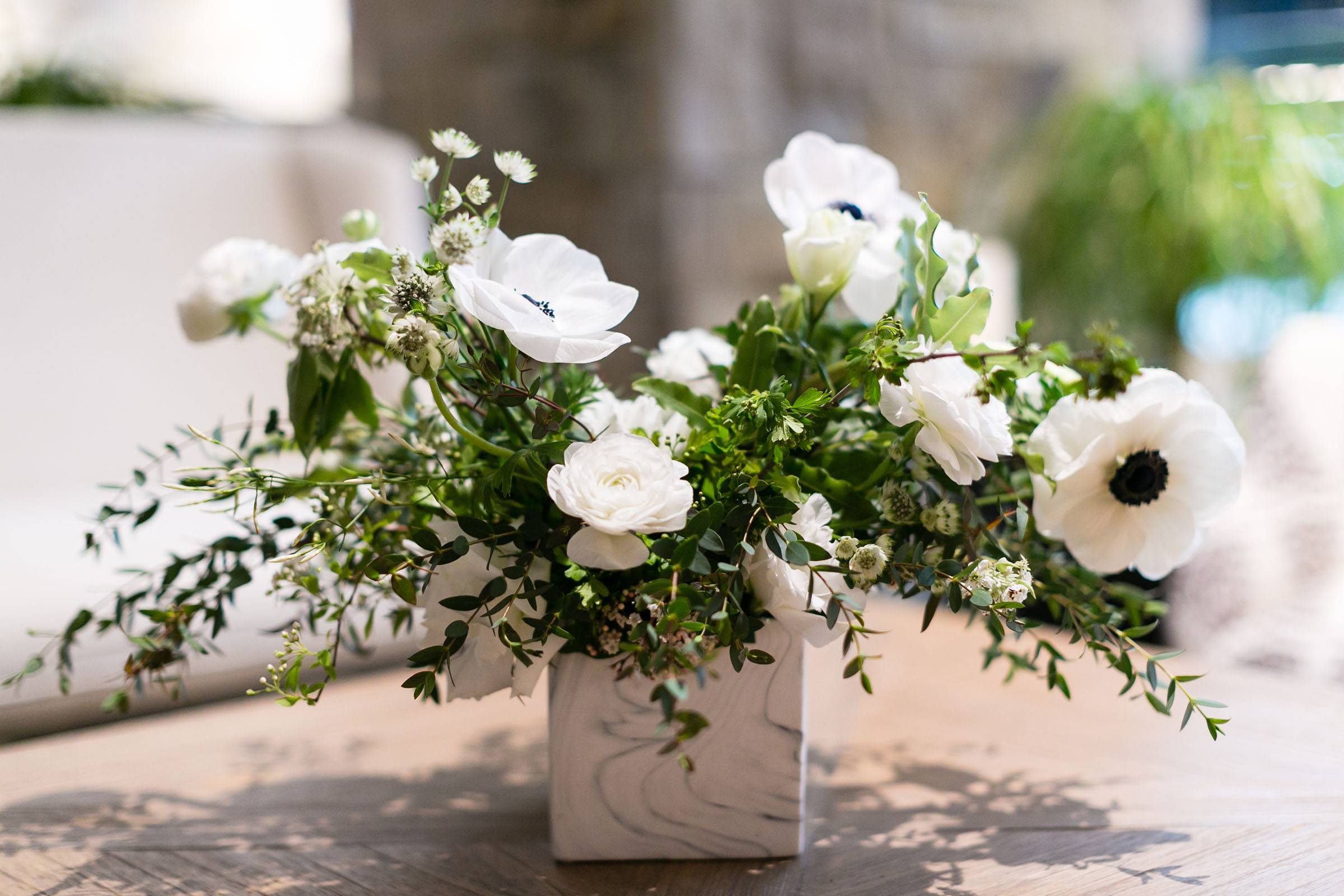 White blooms and greenery in square white container