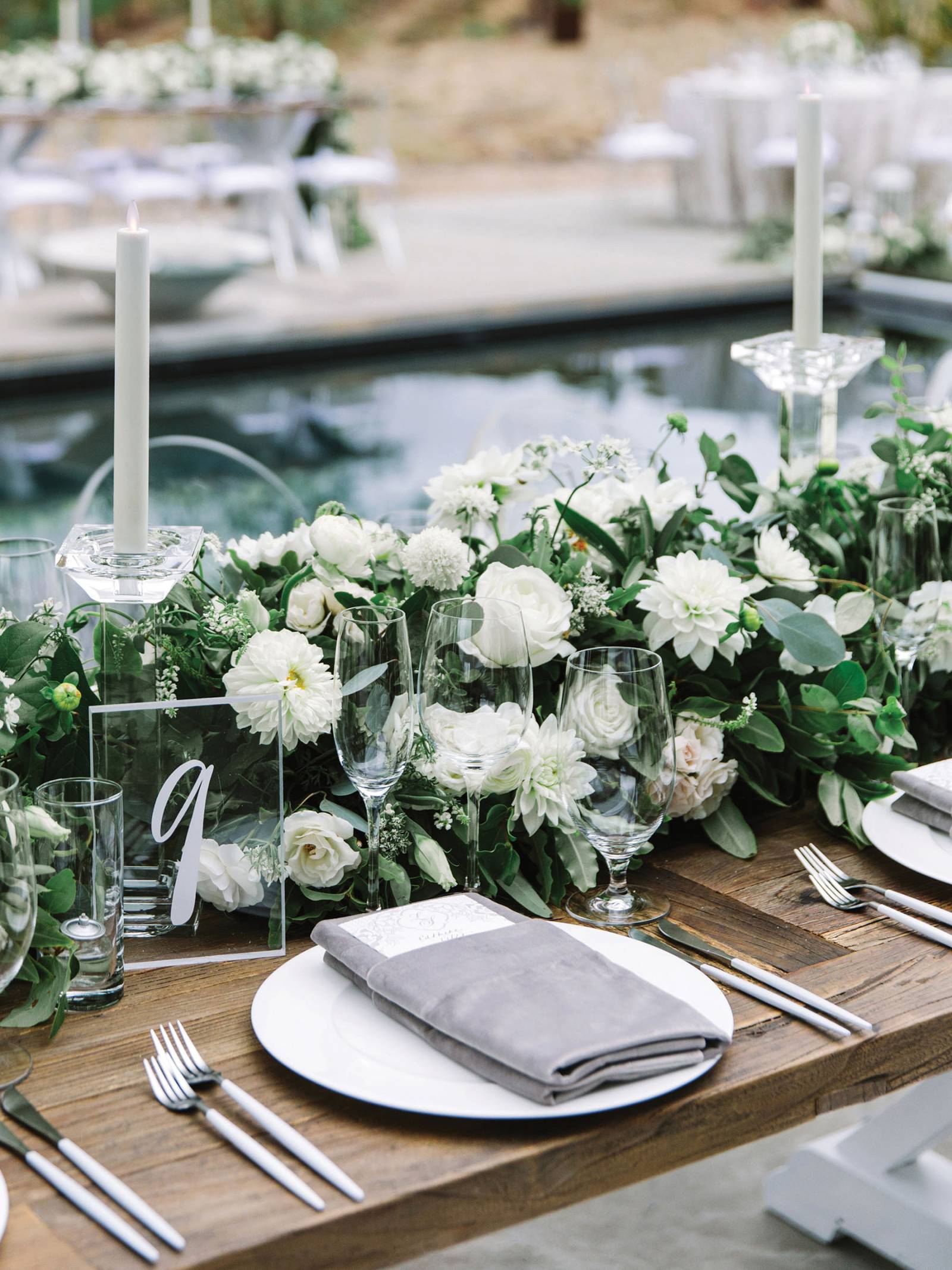 table setting with floral runner of white blooms and greenery