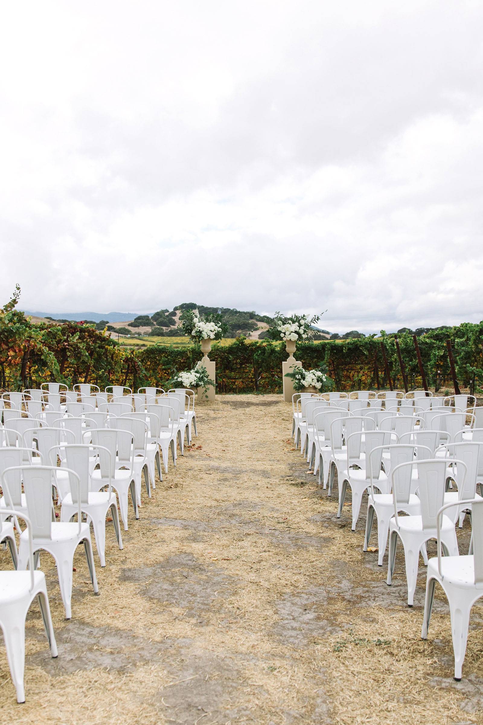 outdoor ceremony setting with white metal chairs