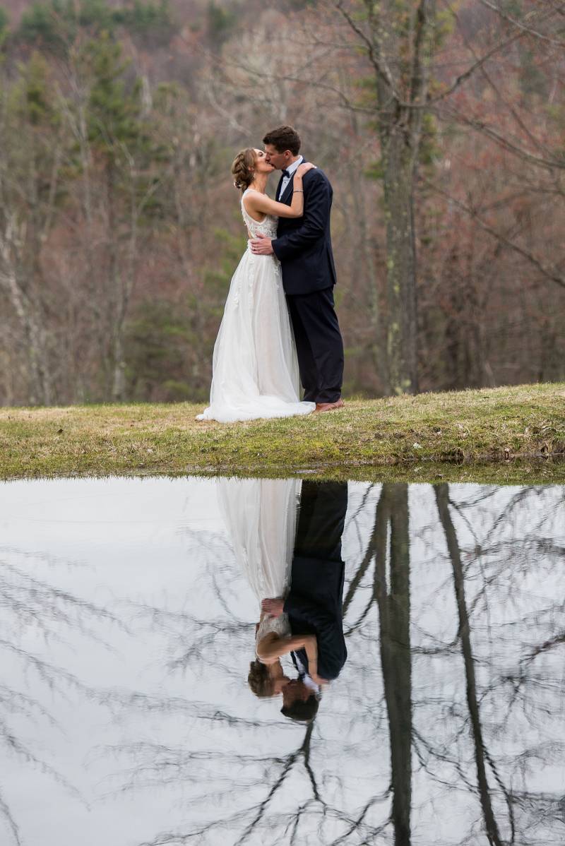 Portrait of bride and groom kissing, reflected in pond at Sleepy Hollow Inn in Vermont on spring wed