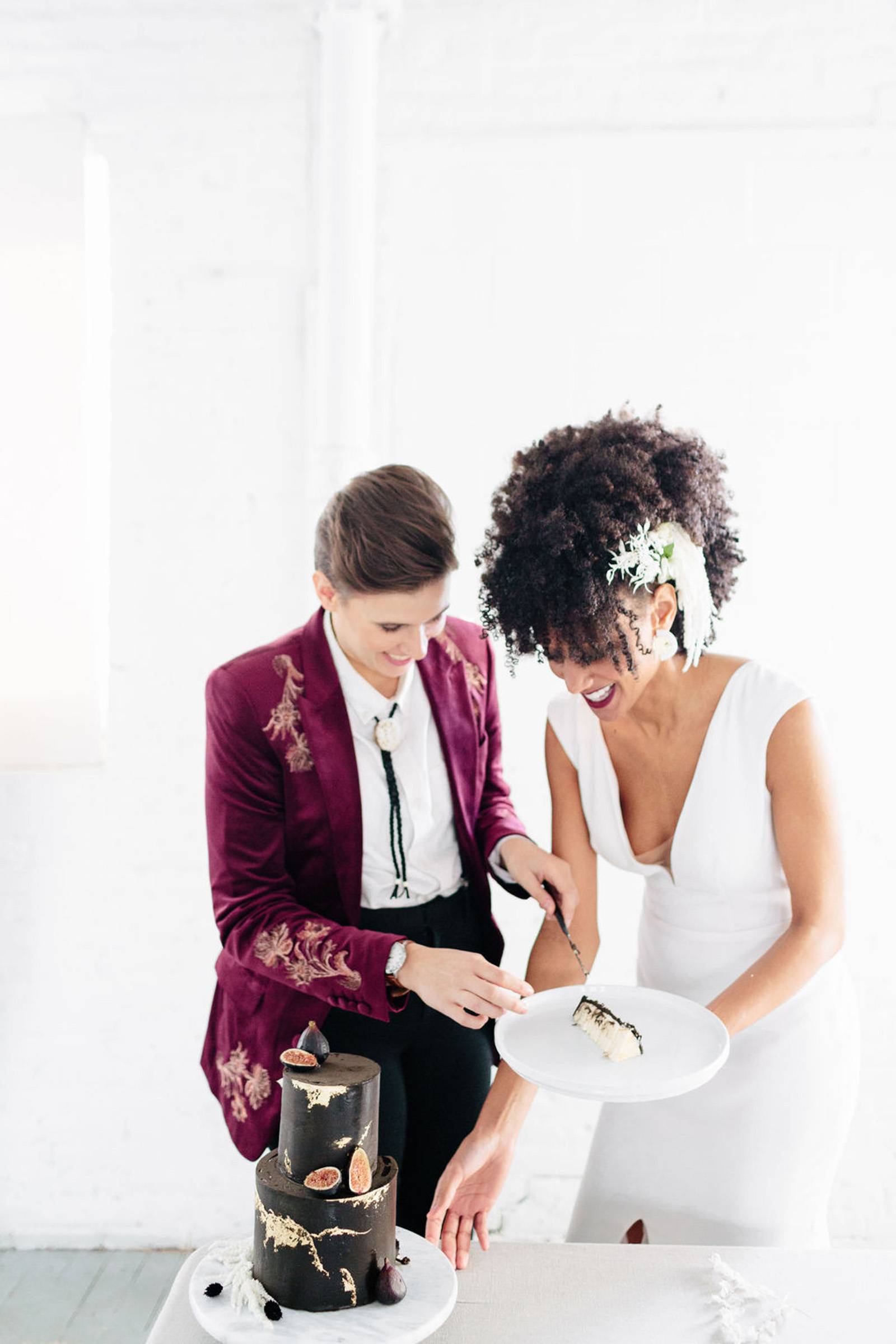 Couple enjoying modern, moody dark wedding cake with gold details