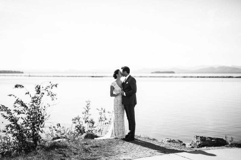 Black and white portrait of couple kissing by Lake Champlain on their wedding day