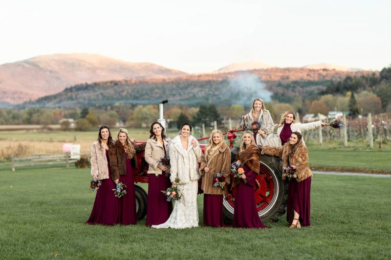 Bride and bridesmaids in wine colored dresses and fur coats during fall wedding at the Boyden Barn