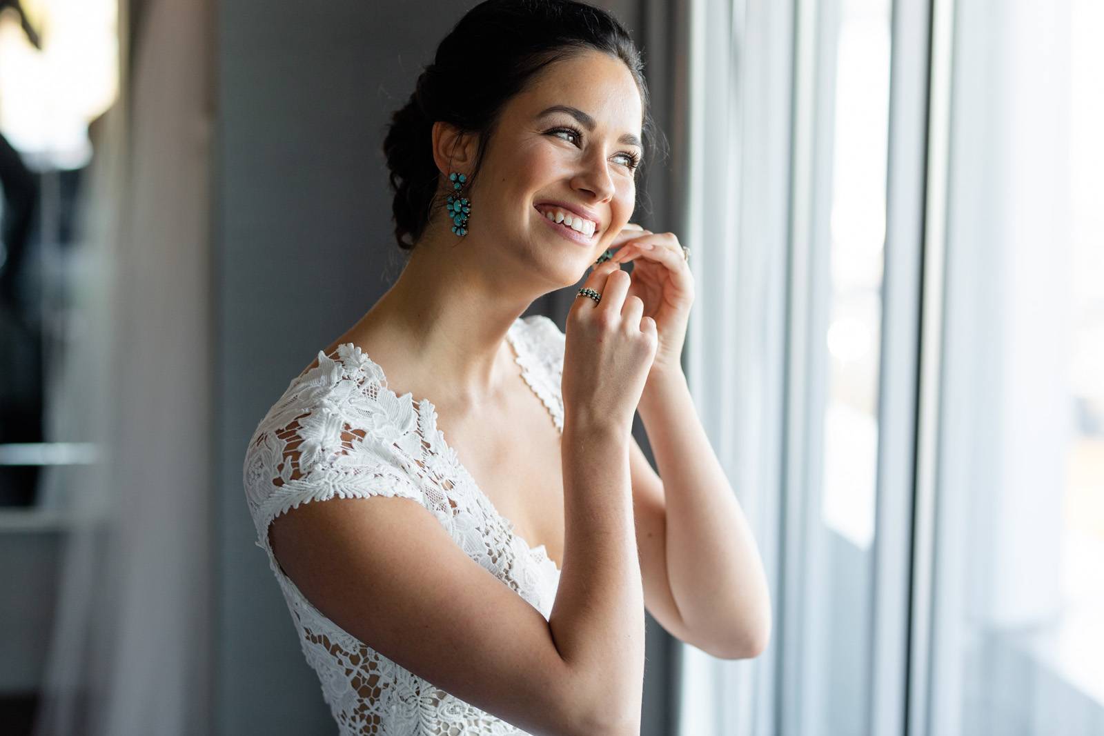 Bridal portrait as bride puts on wedding earrings