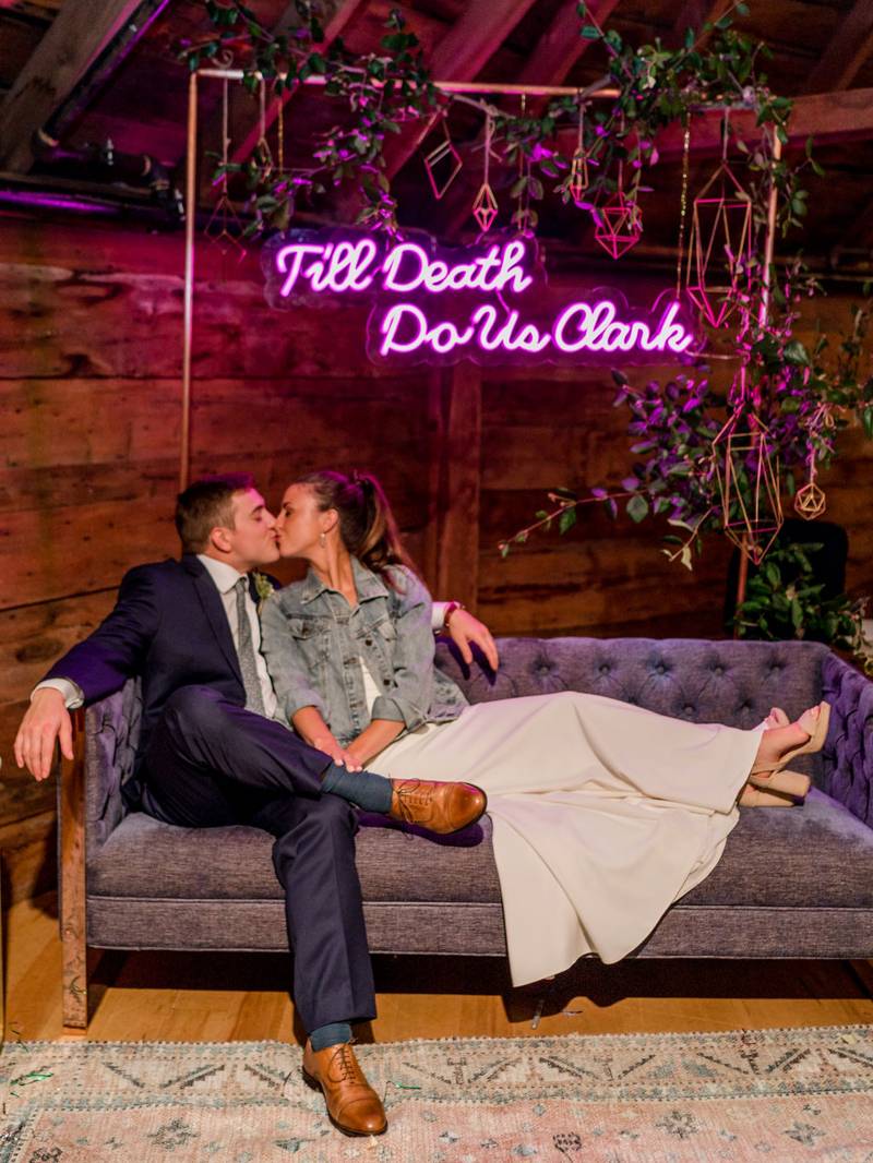 Couple sitting on lounge furniture under custom wedding hashtag neon sign at the Inn at the Round Ba