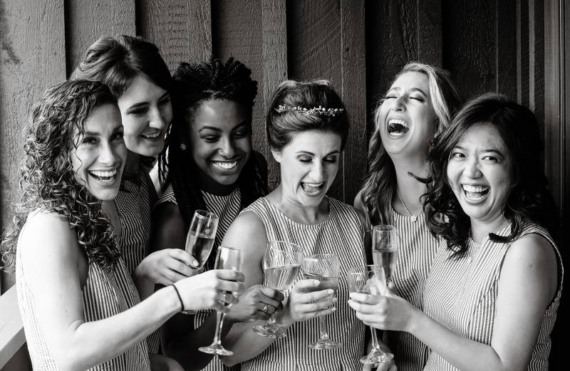 Bride laughing with bridesmaids over mimosas
