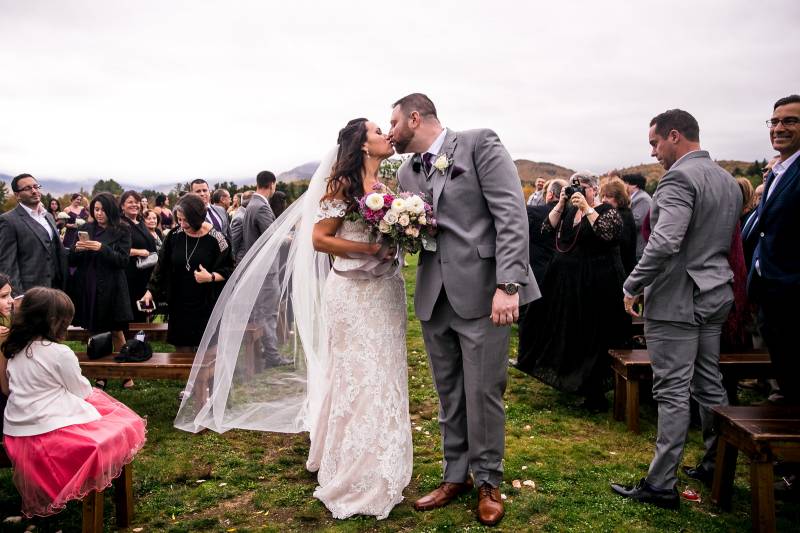 Bride and groom walking down aisle and kissing during fall wedding at the Barn at Smuggler's Notch i