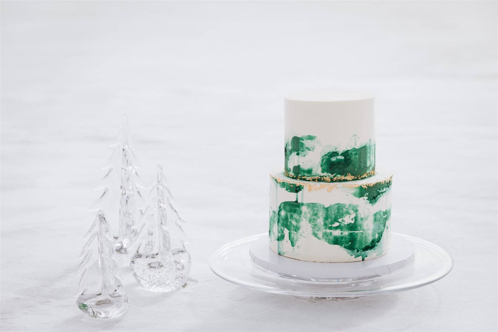 Simon Pearce glass trees next to white and green wedding cake by North Country Cakes on frozen Lake 