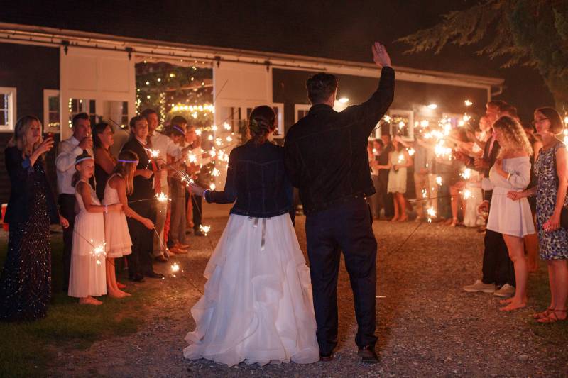 Bride and groom sparkler exit with bridal denim jacket
