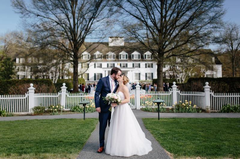 Bride and groom kissing in front of the Woodstock Inn in Vermont during spring wedding