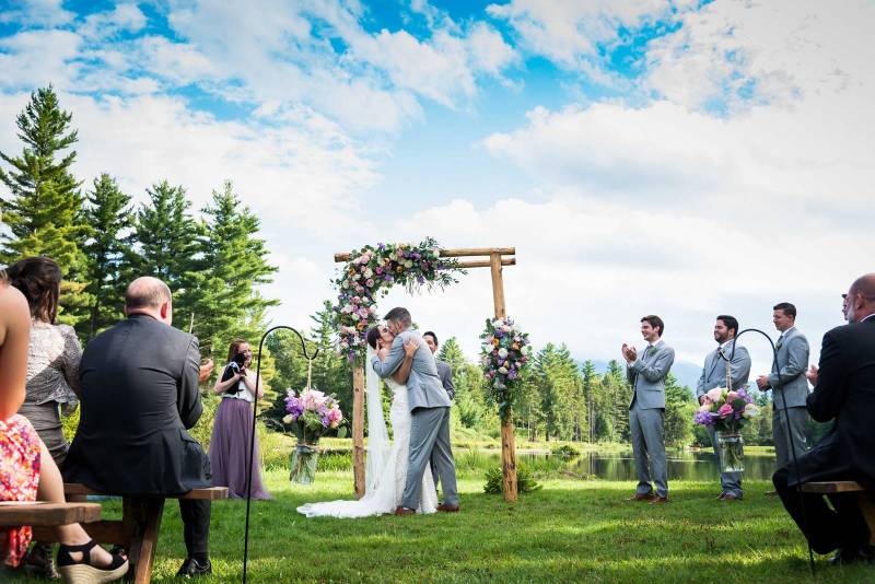 Couple kissing under ceremony arch at Sterling Ridge Resort in Jeffersonville Vermont