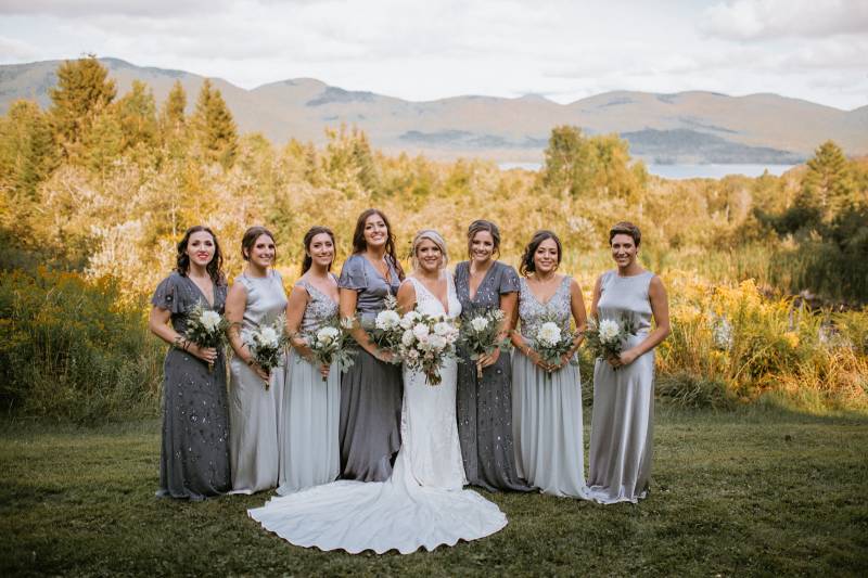 Grey coordinated bridesmaid dresses with white lush bouquets featured in bridal party portrait at th