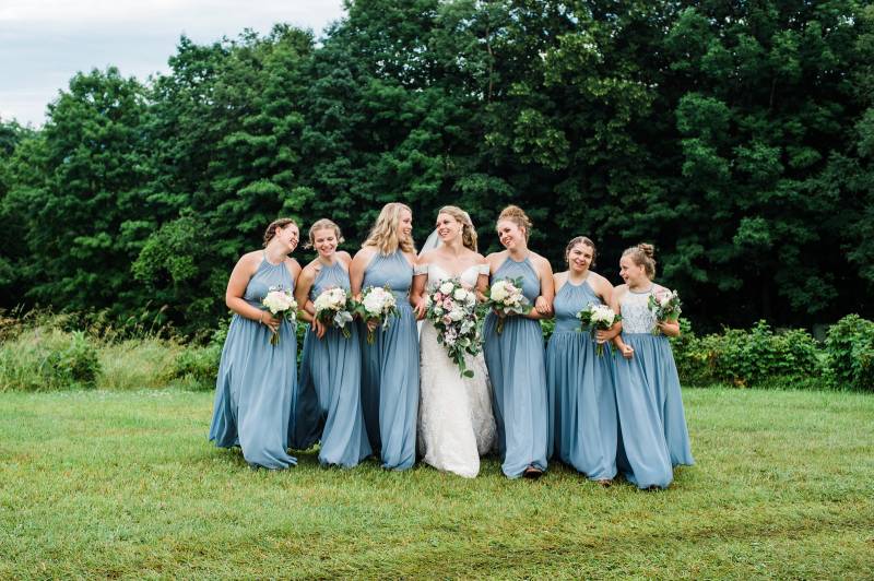 Bride with bridesmaids in dusty blue bridesmaid dresses for summer wedding