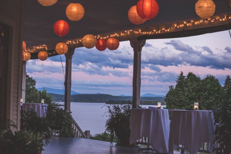 Evening view with glowing paper lanterns hung from ceiling of wraparound porch at the Grand Isle Lak
