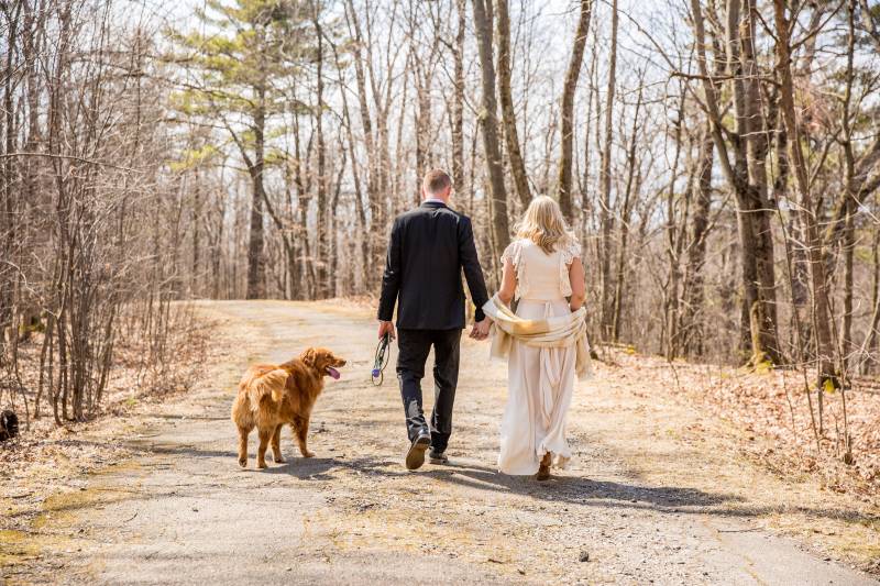 Couple walking through woods with dog after intimate elopement ceremony in Ethan Allen Park in Burli