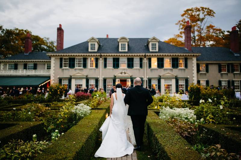 Bride and groom walking toward mansion at the Hildene during elegant fall wedding