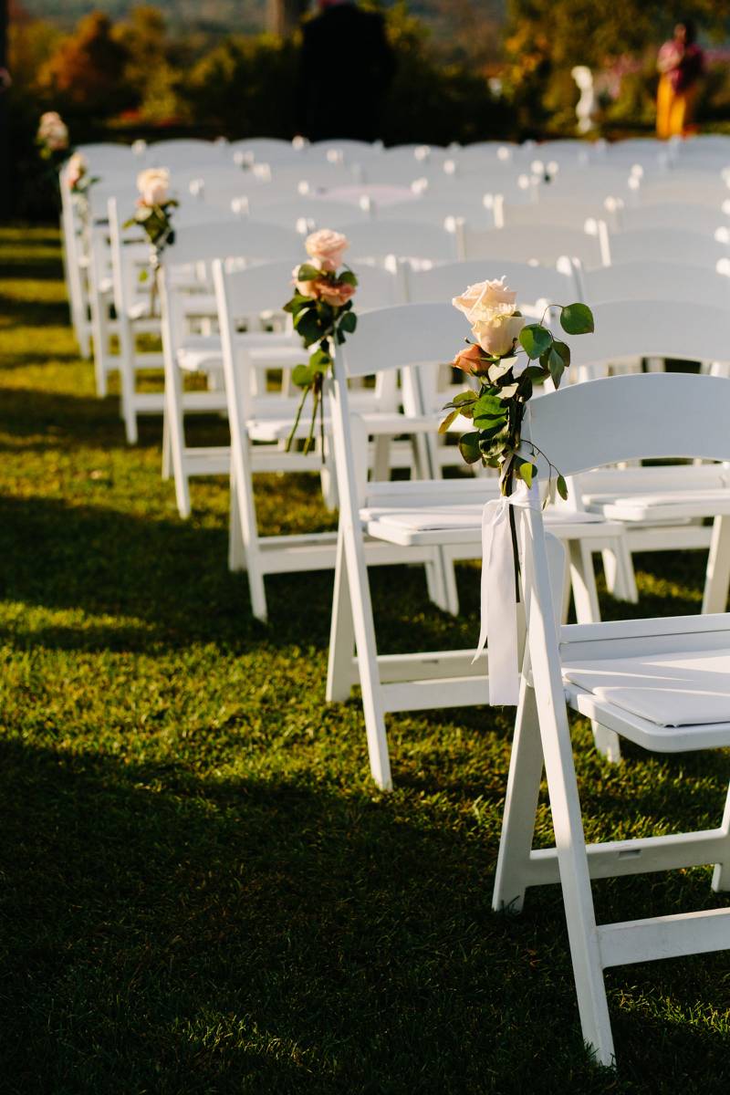 Roses tied onto aisle chairs for outdoor fall black tie wedding ceremony at Hildene